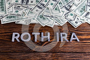 Words ROTH IRA laid on wooden surface by metal letters with us dollar banknotes photo