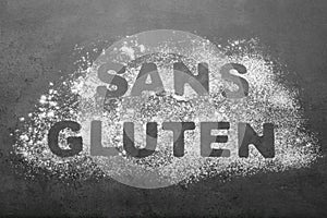 Words Sans gluten written with flour on grey background, top view