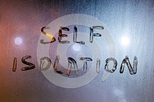 The words self isolation handwritten on wet window glass at night - close-up fuul frame picture with selective focus