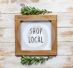 The words `Shop Local` in black text on a framed white board