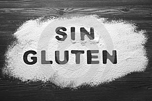 Words Sin gluten written with flour on dark wooden table, top view