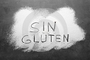 Words Sin gluten written with flour on grey background, top view photo