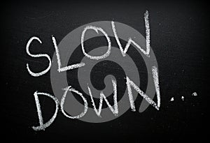 The words Slow Down written on a Blackboard