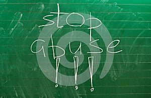 The words STOP ABUSE written on the green school board