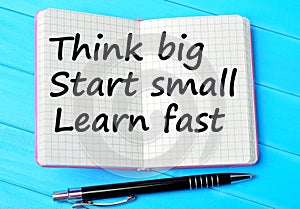 The words Think big Start small Learn fast on notebook