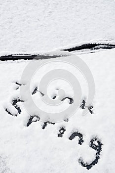 The words `think spring` written in fresh snow on a car hood after a spring storm