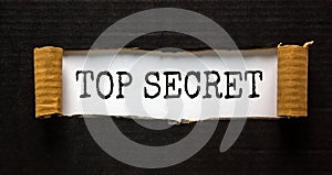 The words `top secret` appearing behind torn black paper. Business concept