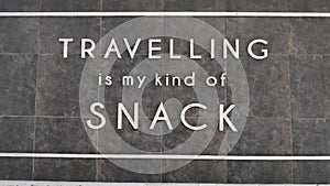 The words `Traveling is My Snack` on the wooden boards