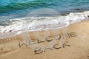 Words Welcome Back are written in the sand on the beach for the tourists, reopen after the coronavirus pandemic, sea holidays are