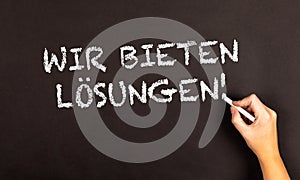 Words  Wir Bieten Losungen written on a blackboard photo