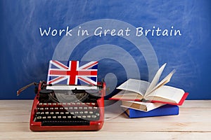 work abroad concept - typewriter, flag of Great Britain, books on table and blackboard with text & x22;Work in Great Britain