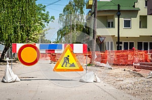 Work ahead street district heating pipeline reconstruction site with sign and fence as road barricade