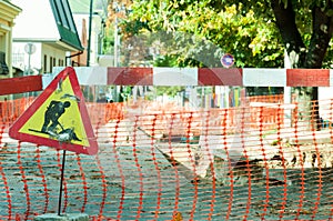 Work ahead street reconstruction site with sign and fence as road barricade