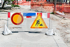 Work ahead street reconstruction site with sign and fence as road barricade