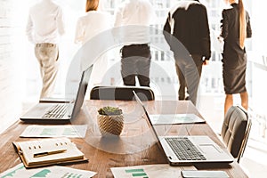 Work area on the table in the foreground. A team of young businessmen working and communicating together in an office