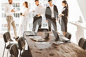 Work area on the table in the foreground. A team of young businessmen working and communicating together in an office