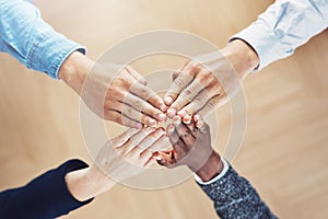 Work as one, get it done. High angle shot of a group of unidentifiable businesspeople joining their hands together in