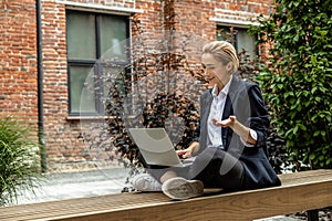 Young business woman sitting in a lotus pose and working on laptop