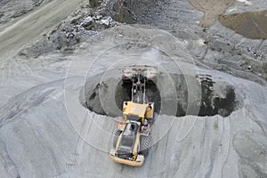 Work of a bulldozer in quarry for the extraction of migmatites and crushed stone