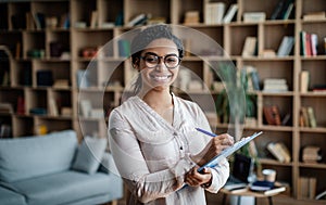 Work and business. Glad smiling millennial black woman psychologist in glasses with tablet look at camera