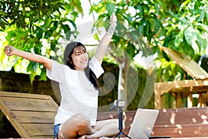 work Cheerful young Asian woman smiling while working on her laptop outside the office, at home, working in the park.