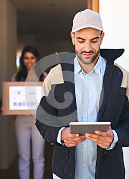 We work with a completely digitized system. Shot of a courier using a digital tablet while making a delivery to a