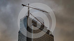 The work of construction cranes on the background of flying clouds, time lapse