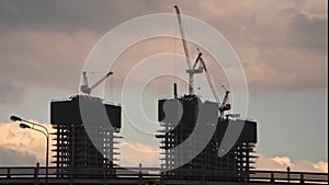 The work of construction cranes on the background of flying clouds, time lapse