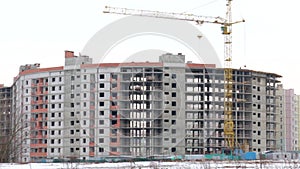 Work on the construction site. Behind the built house. The turning arrow of the construction crane is visible. Sityscape.