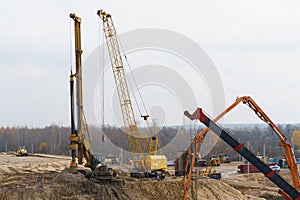 The work of cranes and other equipment at the construction site of the bridge across the river