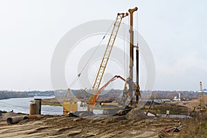 The work of cranes and other equipment at the construction site of the bridge across the river