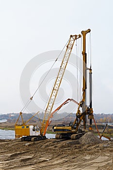 The work of cranes and other equipment at the construction site of the bridge across the river