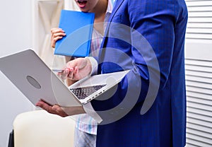 Work culture. Happy creative team working at office. Two joyful young people in formalwear holding laptop, book and