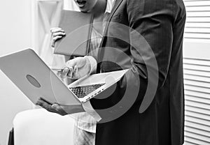 Work culture. Happy creative team working at office. Two joyful young people in formalwear holding laptop, book and