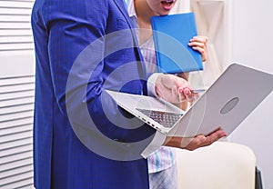 Work culture. Happy creative team working at office. Two joyful young people in formalwear holding laptop, book and
