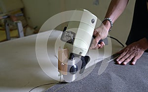 Fabric workers are cutting fabric.