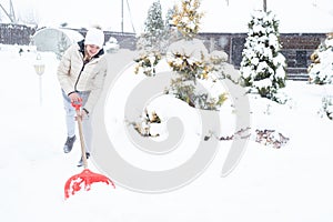 Work at the dacha in winter, a lot of snow. A girl with a shovel cleans the snow in the village.