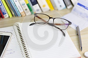 Work desk with book, pen, glasses, and workspace