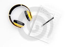 Work desk of modern composer. Music notes near headphones on white background top view