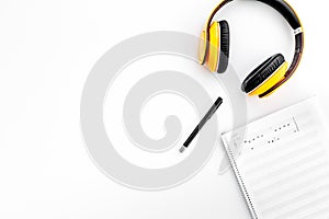 Work desk of modern composer. Music notes near headphones on white background top view copy space