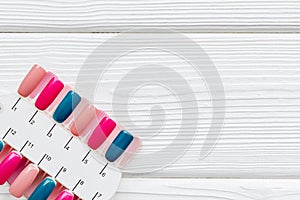Work desk at nail bar with palette of nail polish for manicure on white wooden background top view mockup