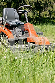 Work in the garden. lawn mower cutting green grass in backyard.