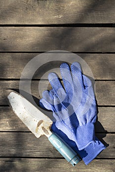 Work gloves and garden shovel on boards, top view, spring gardening concept, copy space