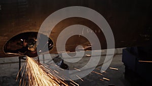 Work grinder cuts metal at the factory. Heavy industry worker cuts a huge pipe