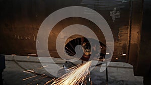 Work grinder cuts metal at the factory. Heavy industry worker cuts a huge pipe
