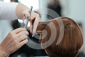 The work of a hairdresser. Hairdresser cut hair of a woman  in a beauty salon. Close-up of hands.