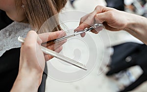 The work of a hairdresser. Hairdresser cut hair of a woman  in a beauty salon. Close-up of hands