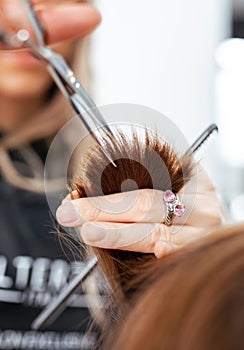 The work of a hairdresser. Hairdresser cut hair of a woman  in a beauty salon. Close-up of hands