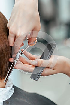 The work of a hairdresser. Hairdresser cut hair of a woman  in a beauty salon. Close-up of hands