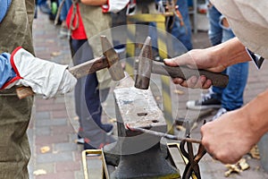 Work with hammers on the anvil in the street.